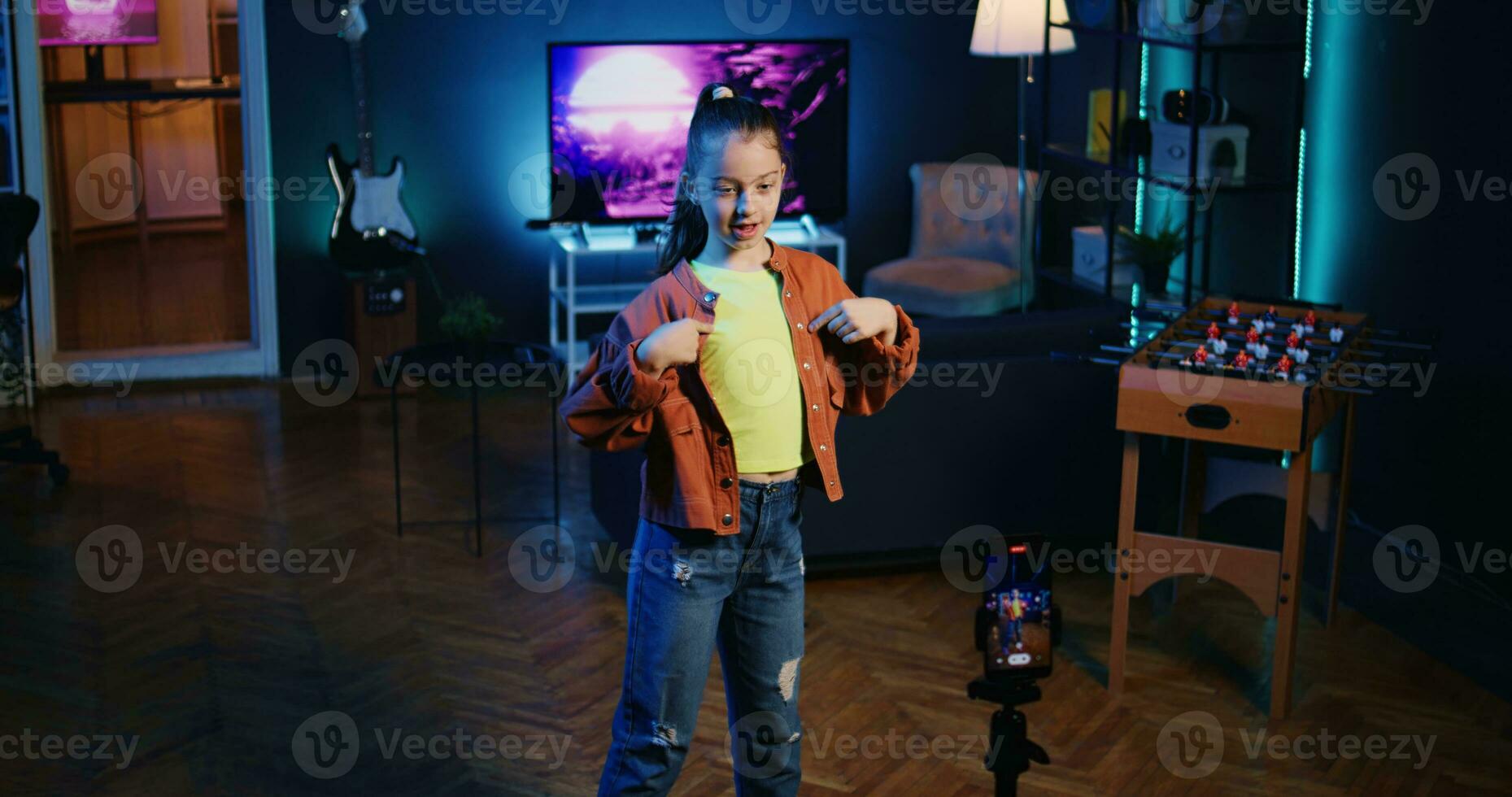 linda joven utilizando móvil teléfono en trípode estabilizador a película danza tutorial para otro niños acecho su en línea social medios de comunicación contenido. niña grabación vídeo con teléfono inteligente focalización gen z espectadores foto