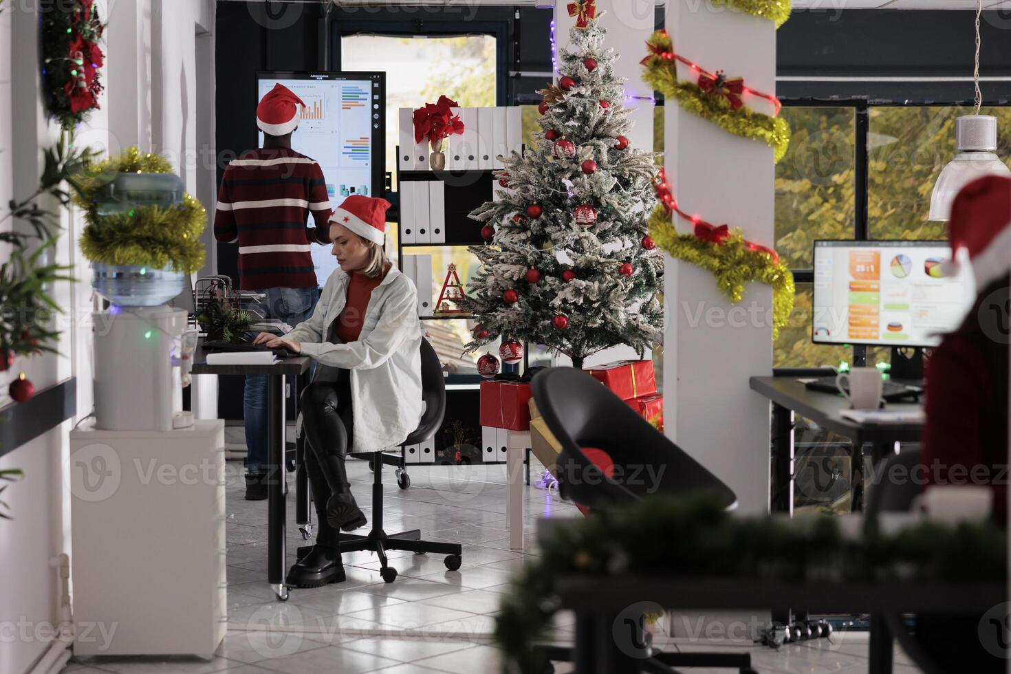 Business team working in busy festive decorated office during Christmas holiday season. Hardworking employees solving various company project tasks in xmas ornate workspace photo