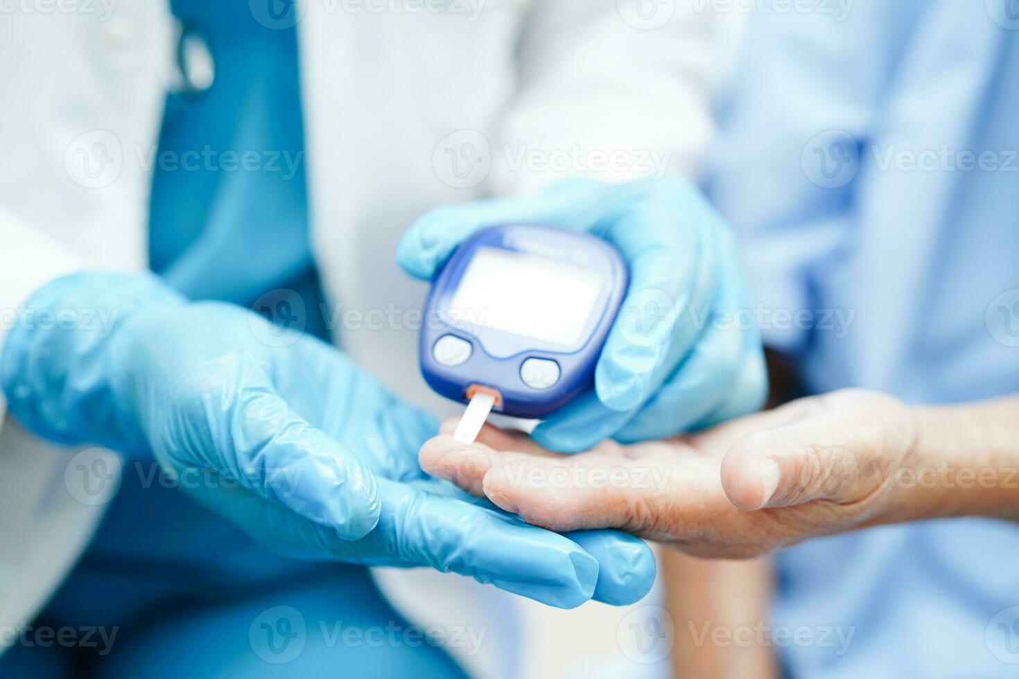 Asian doctor using digital glucose meter for check sample blood sugar level to treatment diabetes. photo