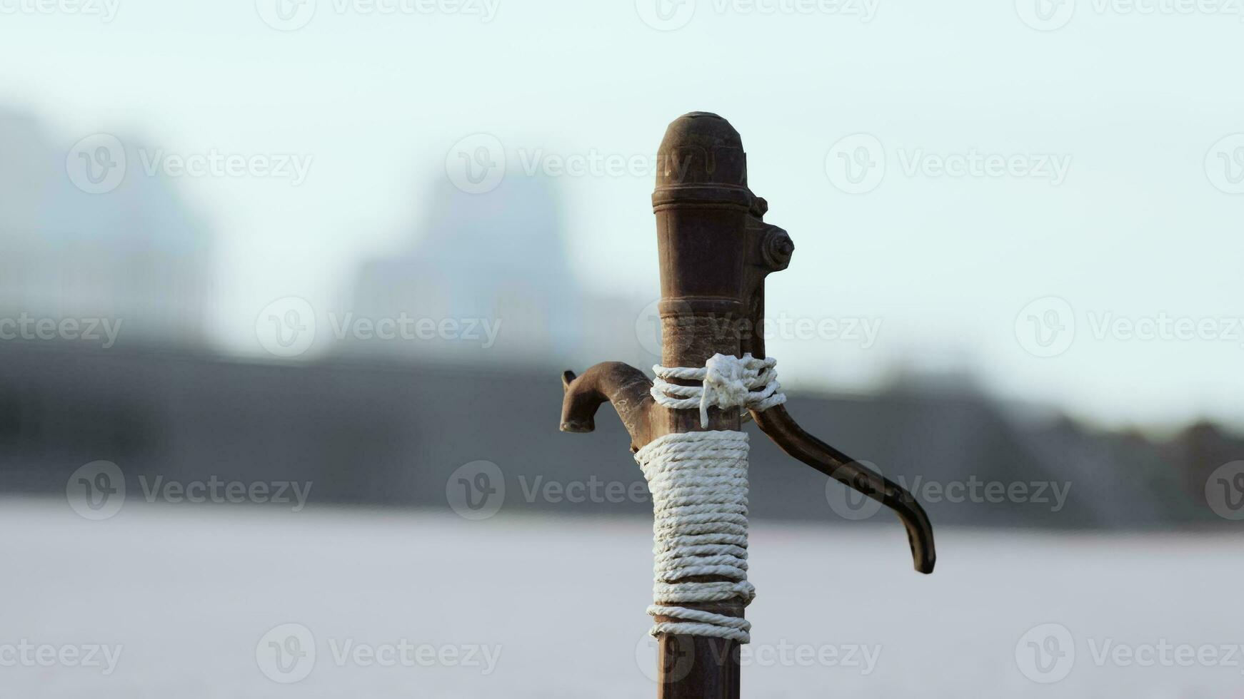 Rusty old metal water pump on sand beach photo