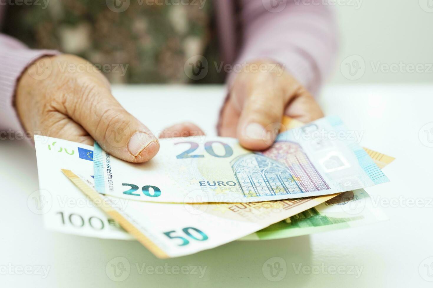 Retired elderly woman holding Euro banknotes money and worry about monthly expenses and treatment fee payment. photo