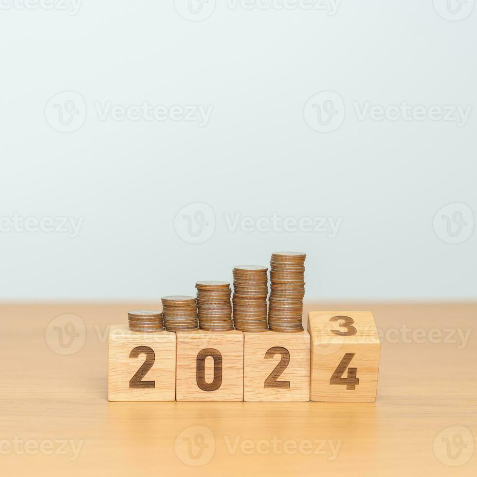 flipping 2023 to 2024 year block with Coins stack. Money, Budget, tax, investment, financial, savings and New Year Resolution concepts photo