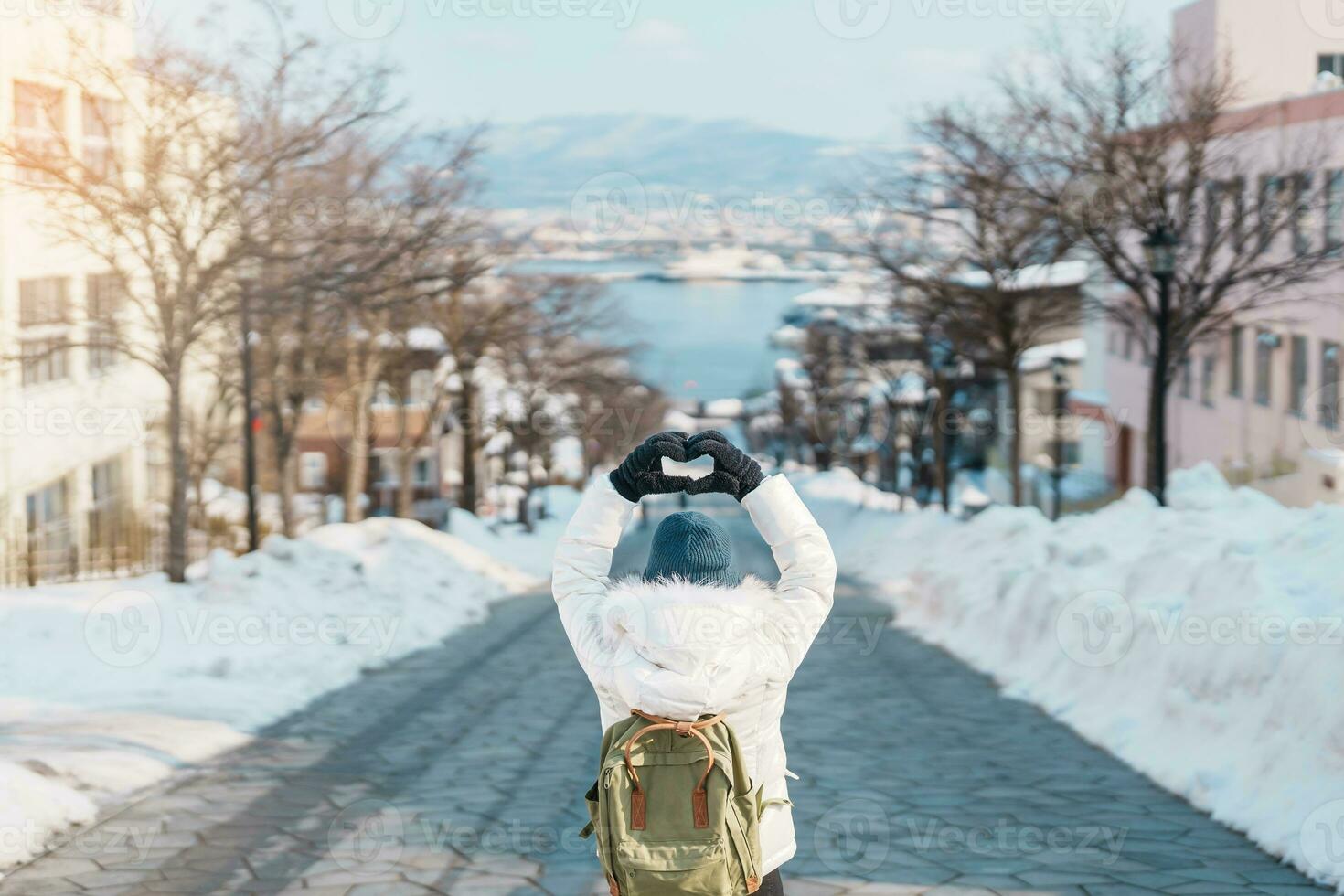 Woman tourist Visiting in Hakodate, Traveler in Sweater sightseeing Hachiman Zaka Slope with Snow in winter. landmark and popular for attractions in Hokkaido, Japan. Travel and Vacation concept photo