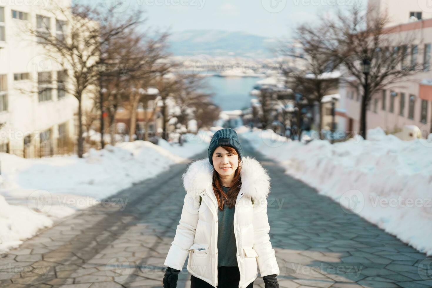 Woman tourist Visiting in Hakodate, Traveler in Sweater sightseeing Hachiman Zaka Slope with Snow in winter. landmark and popular for attractions in Hokkaido, Japan. Travel and Vacation concept photo