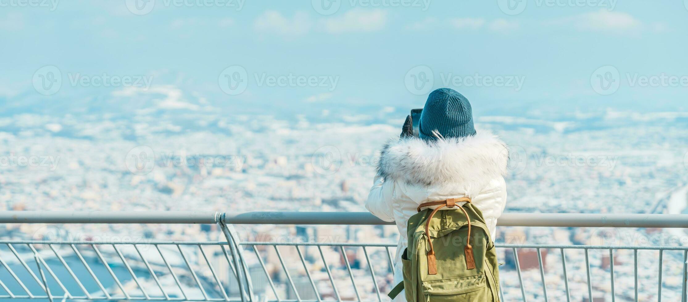 Woman tourist Visiting in Hakodate, Traveler in Sweater sightseeing view from Hakodate mountain with Snow in winter. landmark and popular for attractions in Hokkaido, Japan.Travel and Vacation concept photo