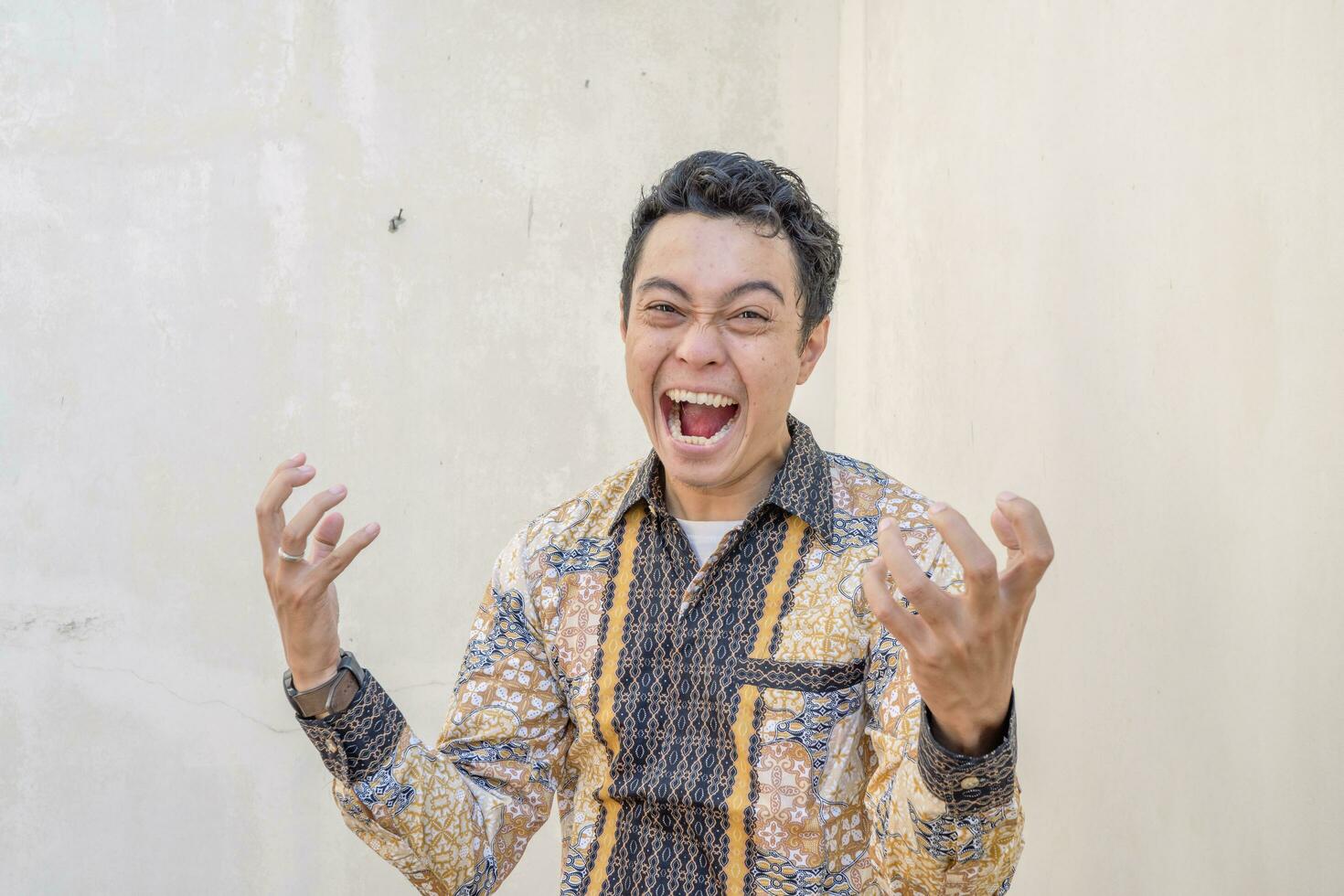 Young Indonesian wear batik traditional culture of Indonesia with rage gesture. photo