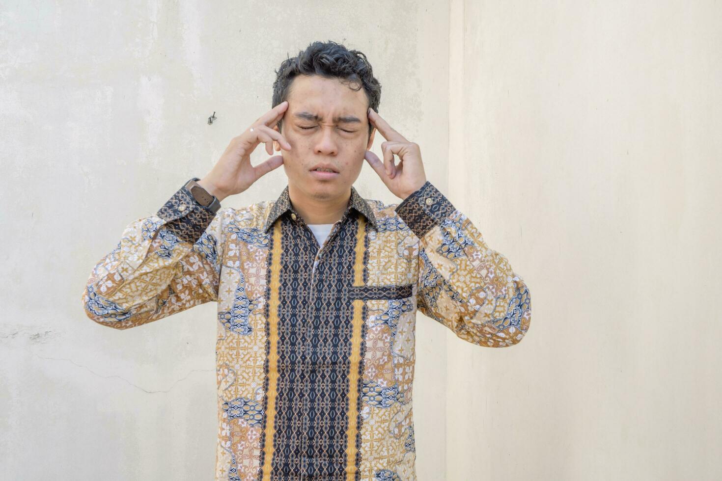 Young Indonesian wear batik traditional culture of Indonesia with dizzy pose. photo