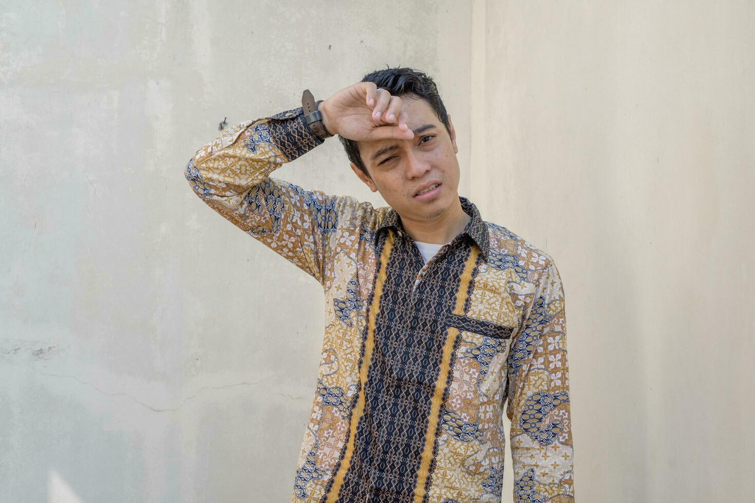 Young Indonesian wear batik traditional culture Indonesia with sweat gesture photo