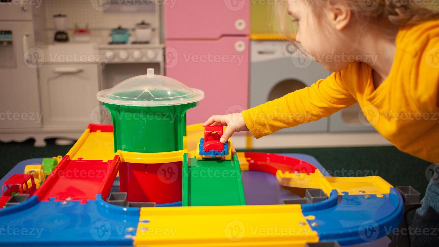 child in kindergarten, playroom, playing with toys, learning. Plays with car, race track, constructor photo