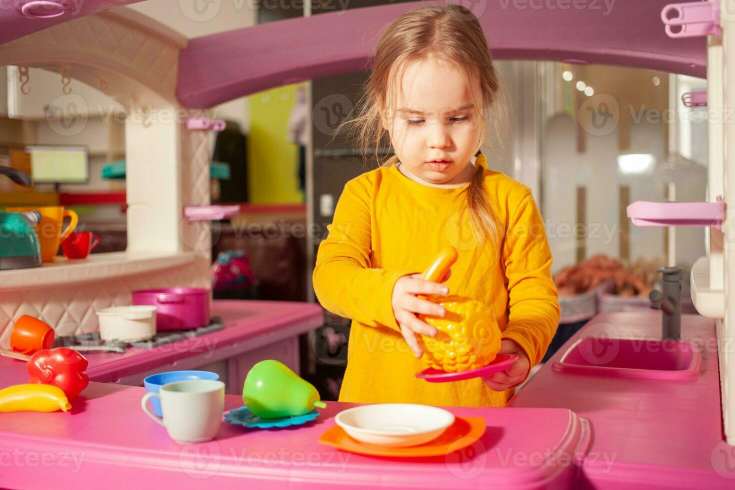 child in kindergarten, playroom, playing with toys, learning. plays in kitchen, cooks vegetables and fruits photo