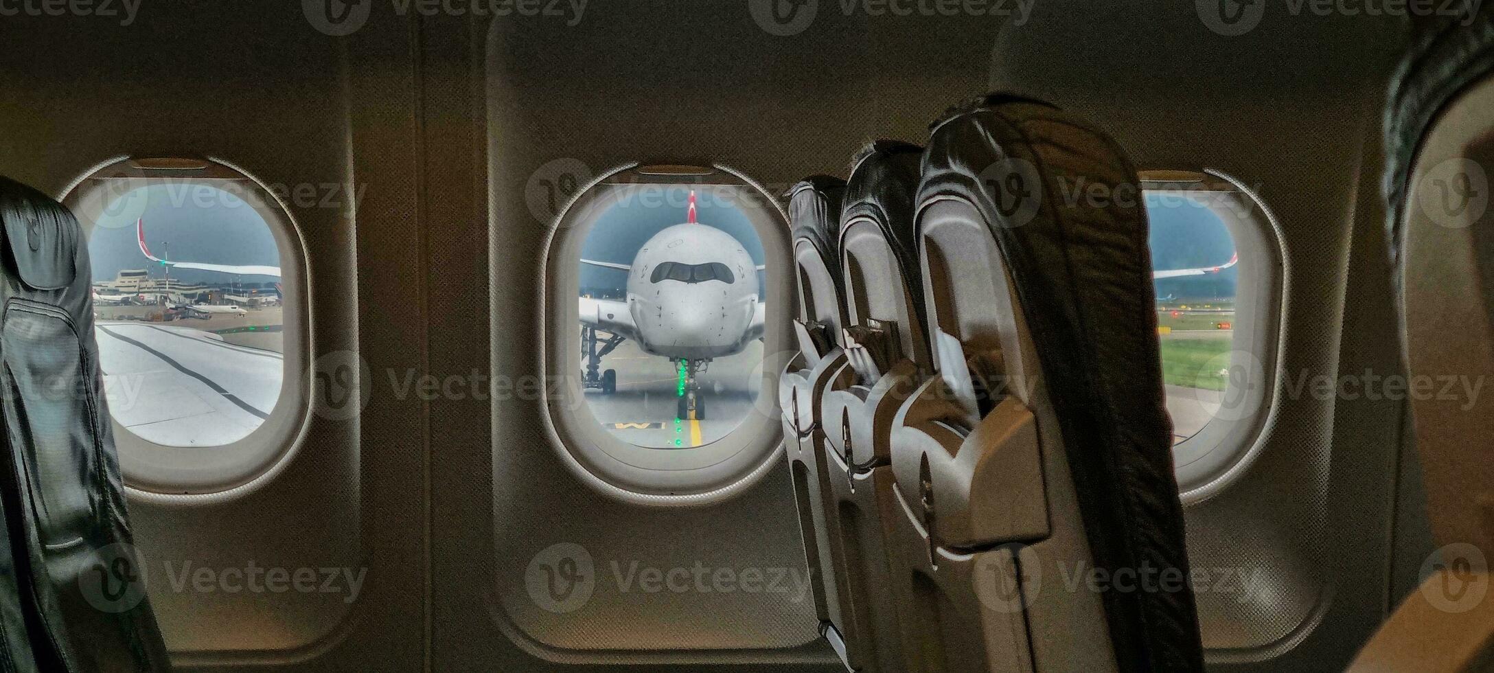 View from an airplane through the cabin windows onto another airplane in frontal view photo