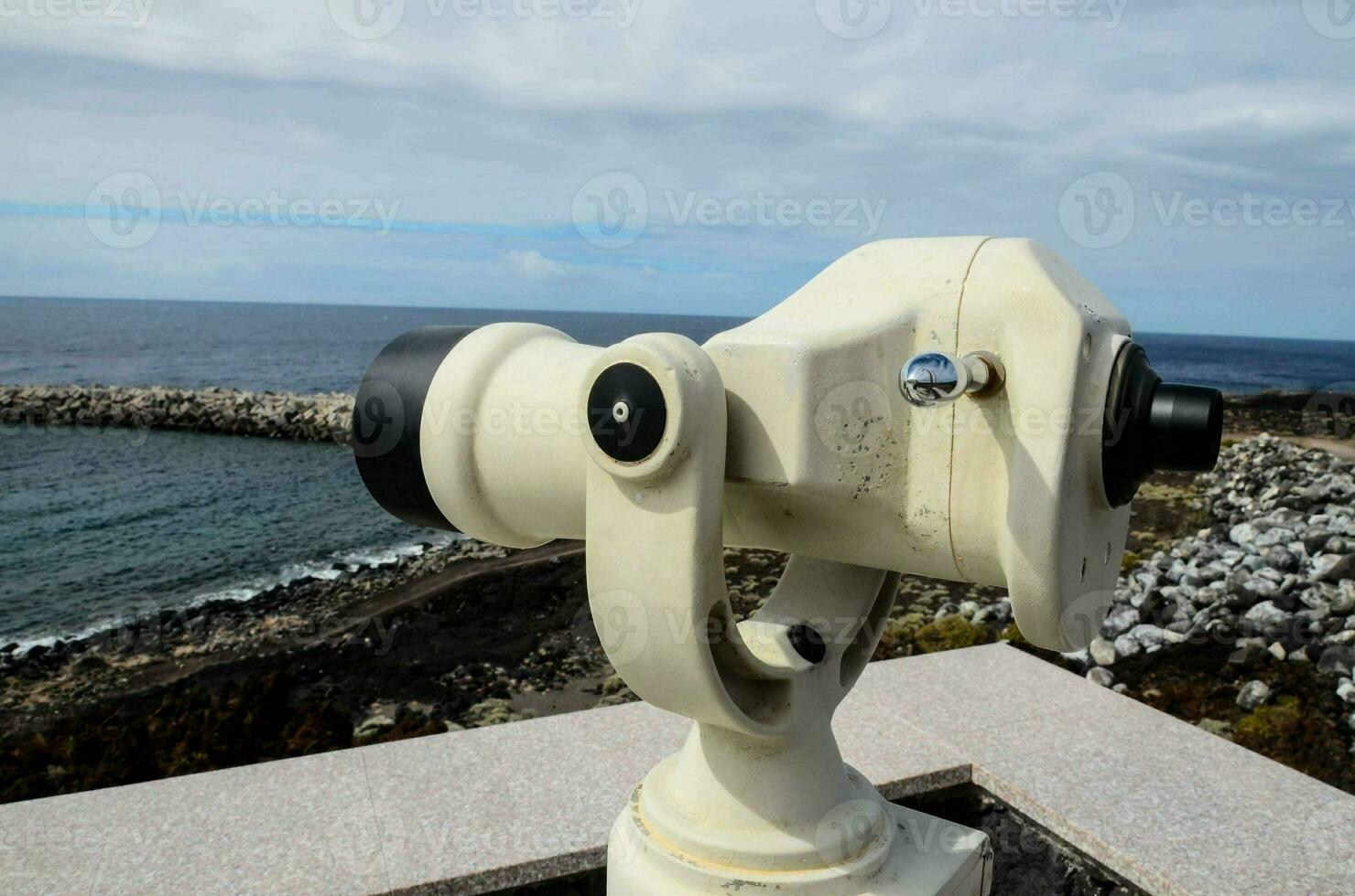 a telescope on a ledge overlooking the ocean photo