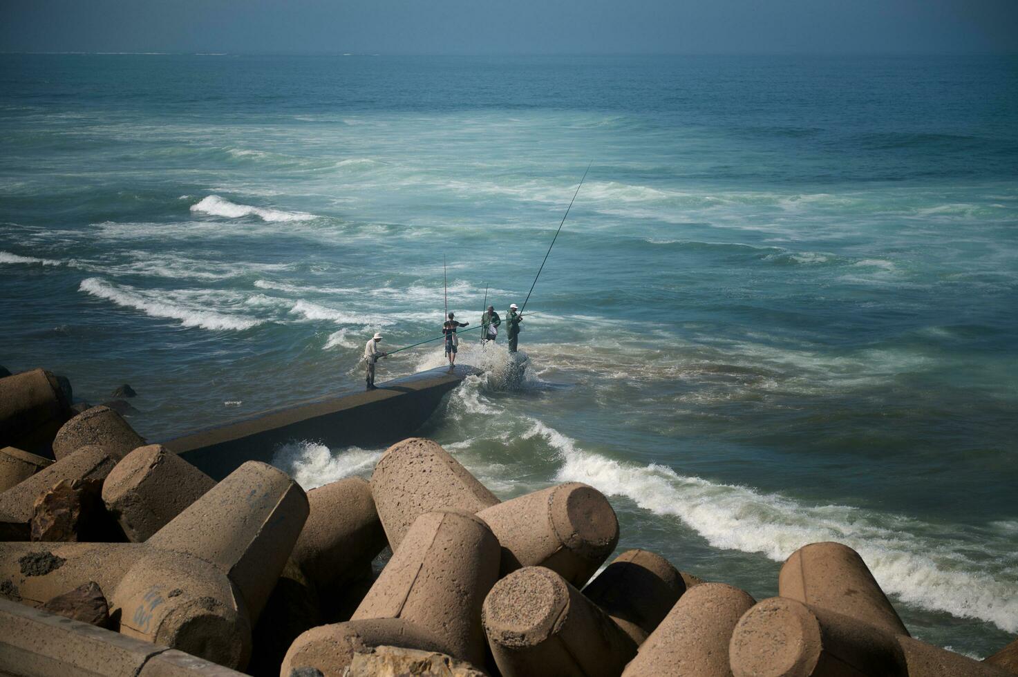 Rear view of unrecognizable people - fisherman standing on the seashore on breakwater and fishing in Atlantic Ocean. People. Leisure. Hobby photo