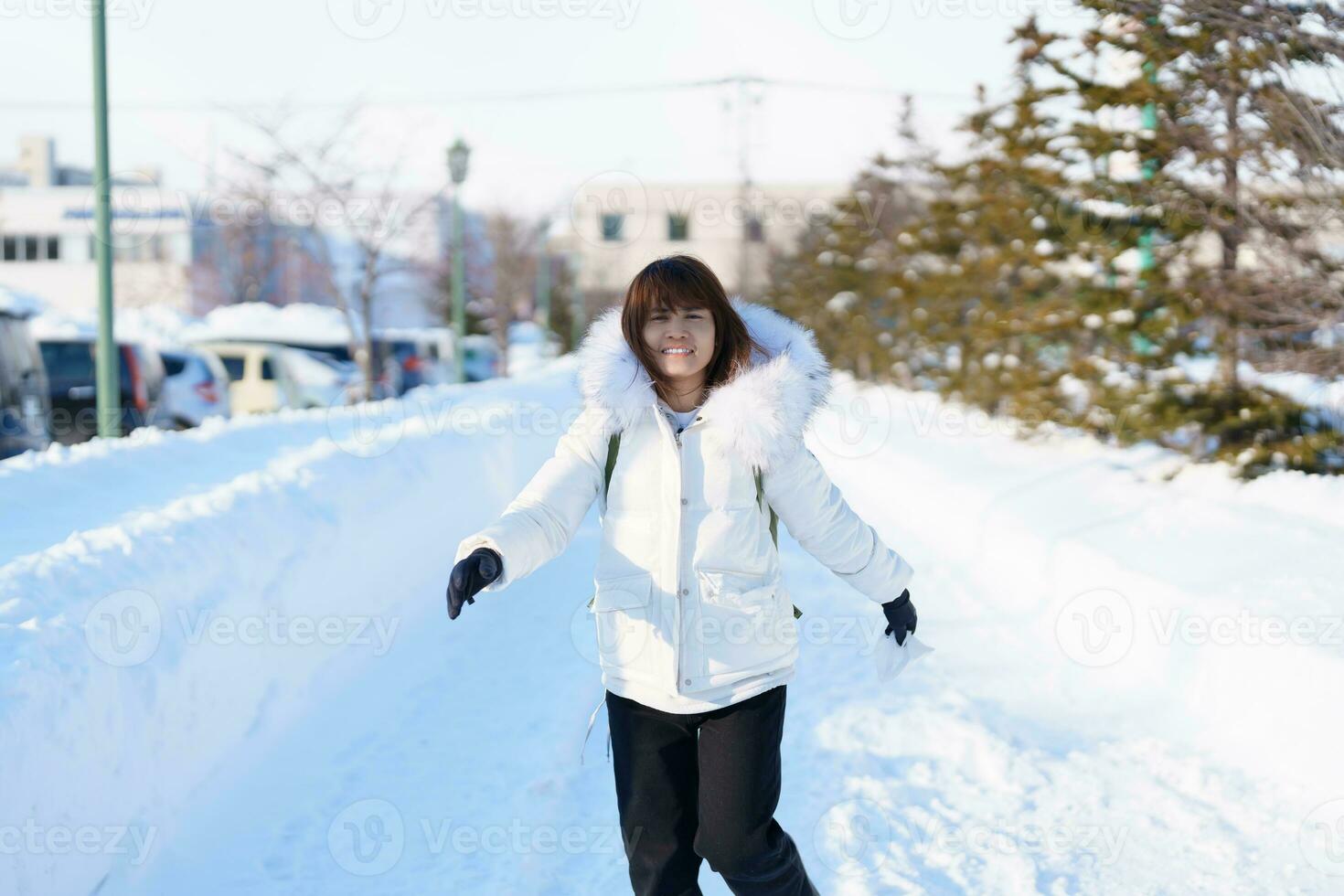 happy Traveler with Sweater and backpack walking on snow covered road in frosty weather, woman tourist sightseeing in Sapporo city, Hokkaido, Japan Winter Travel and Vacation concept photo