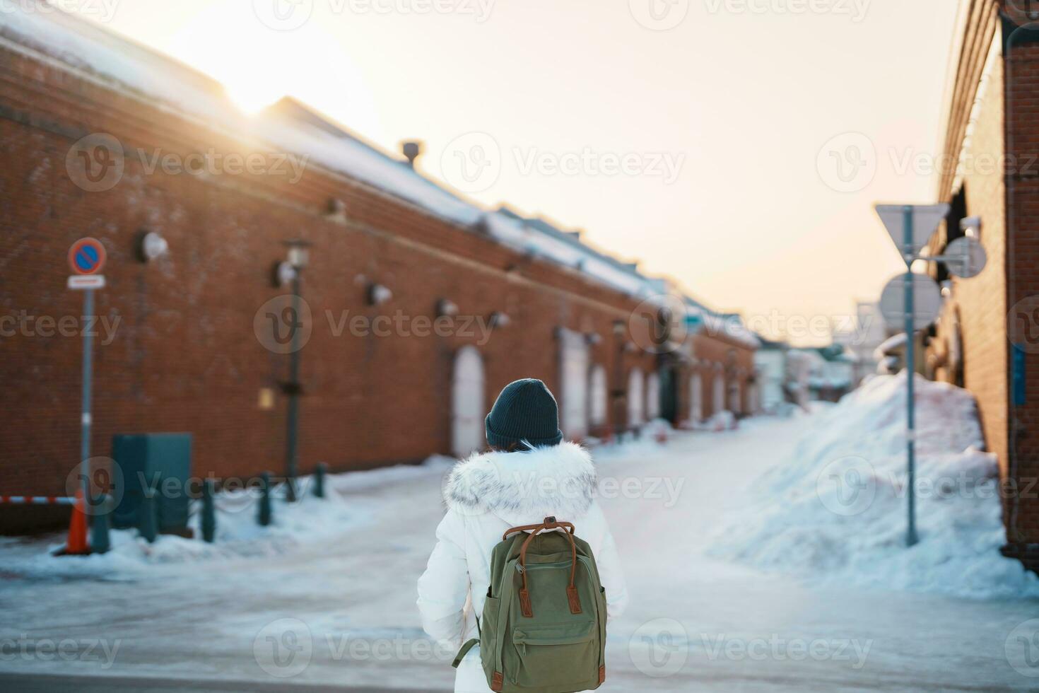 Woman tourist Visiting in Hakodate, Traveler in Sweater sightseeing Kanemori Red Brick Warehouse with Snow in winter. landmark and popular for attractions in Hokkaido,Japan.Travel and Vacation concept photo