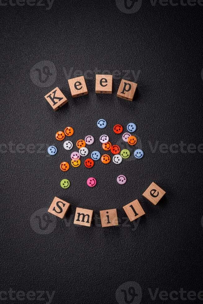 A concept consisting of the inscription of the word smile, with round emoticons on a dark concrete background photo