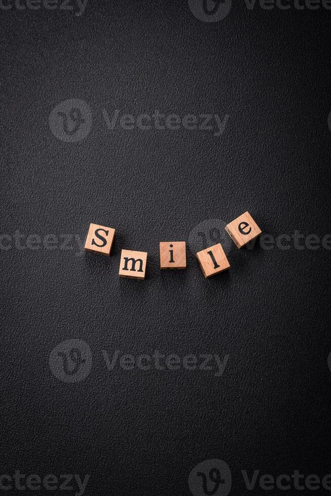 A concept consisting of the inscription of the word smile, with round emoticons on a dark concrete background photo