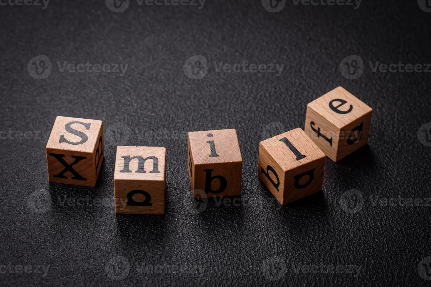 A concept consisting of the inscription of the word smile, with round emoticons on a dark concrete background photo