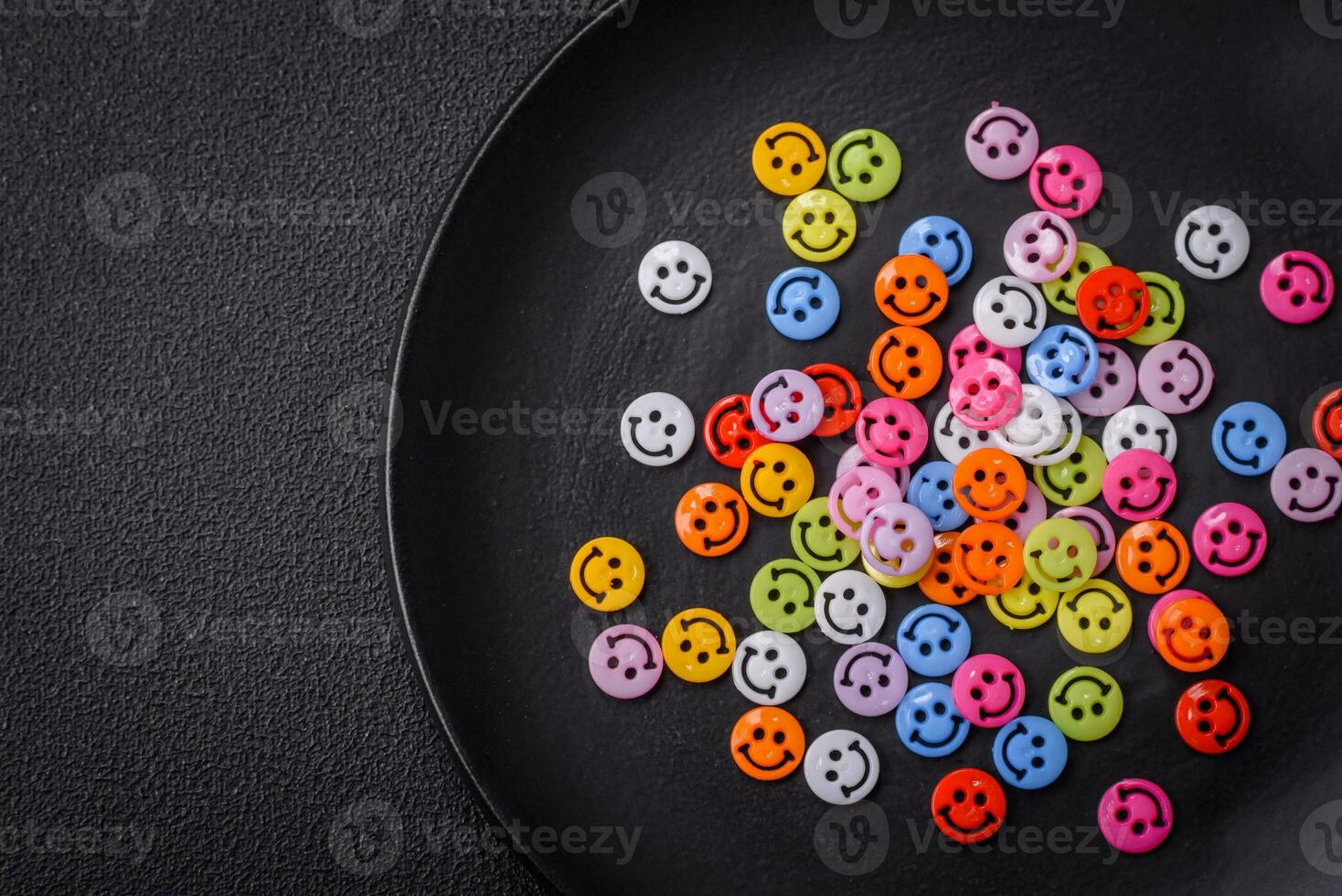 A concept consisting of the inscription of the word smile, with round emoticons on a dark concrete background photo