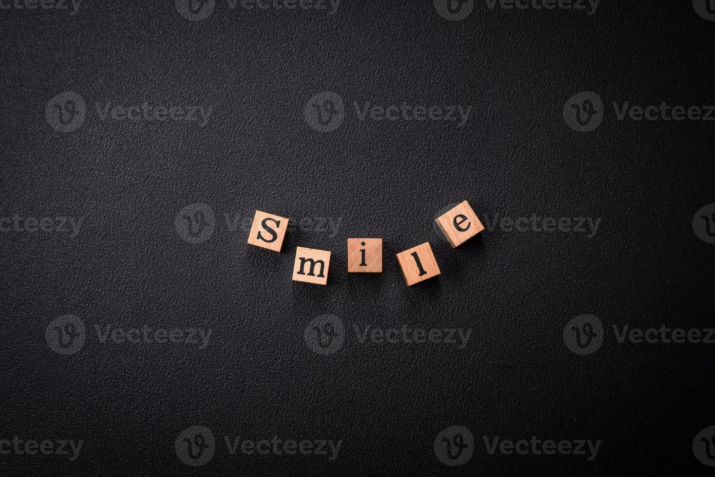 A concept consisting of the inscription of the word smile, with round emoticons on a dark concrete background photo