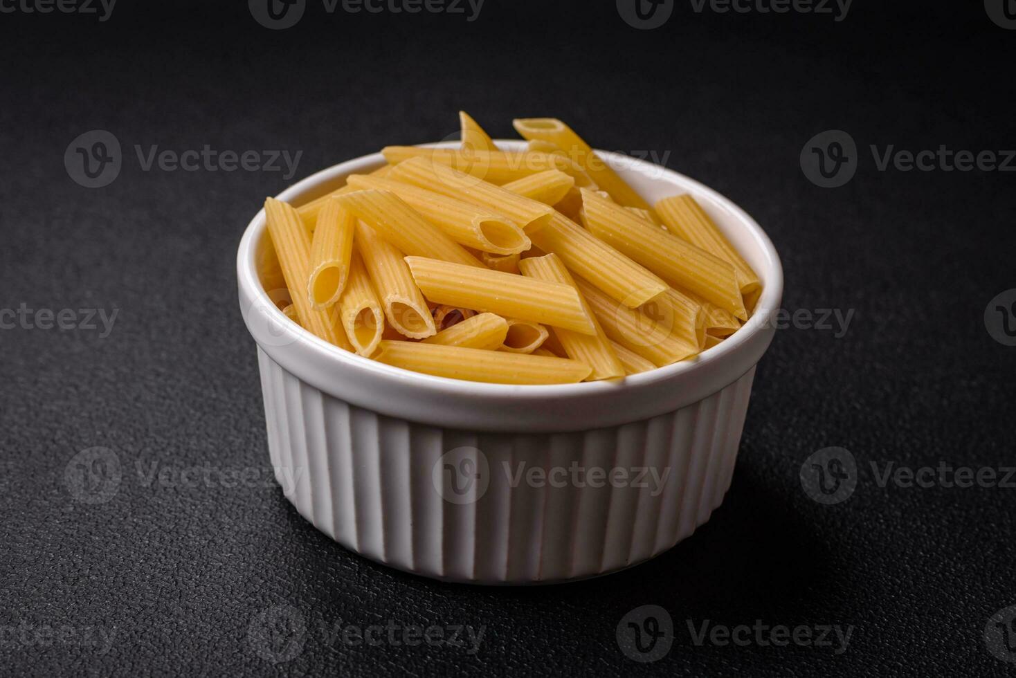 Raw penne pasta from whole grain wheat varieties with salt and spices photo