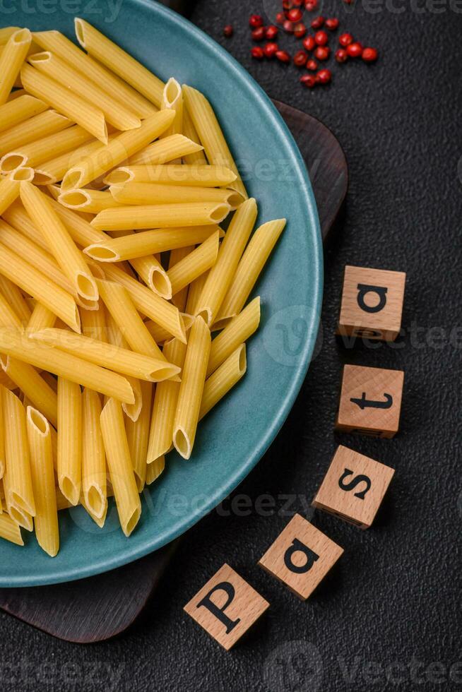 Raw penne pasta from whole grain wheat varieties with salt and spices photo