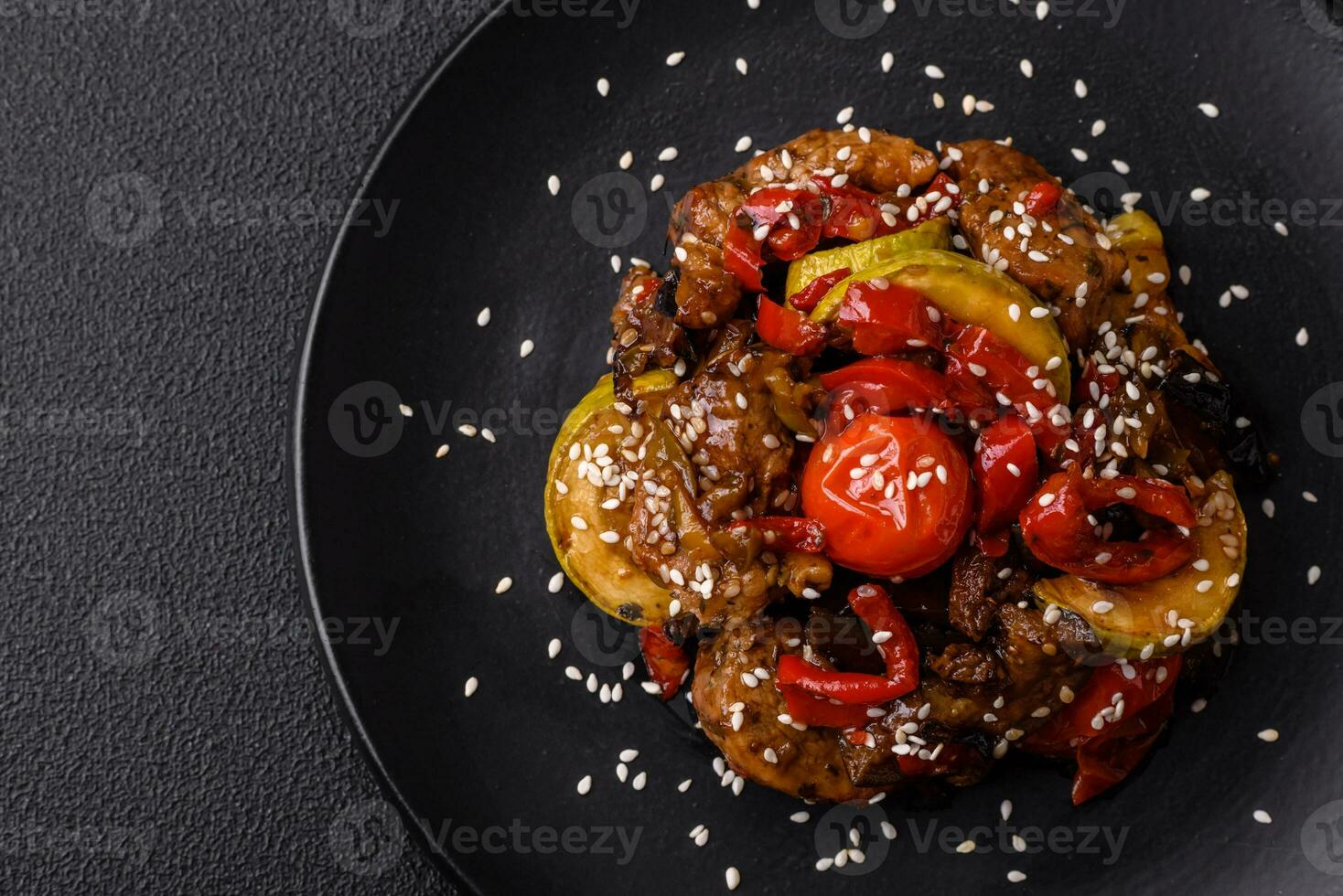 Warm salad with veal, tomatoes, peppers, zucchini, sesame, salt, spices and herbs photo