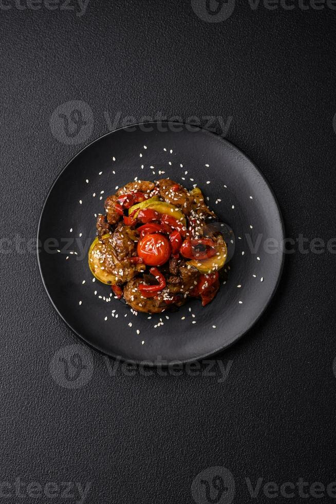 Warm salad with veal, tomatoes, peppers, zucchini, sesame, salt, spices and herbs photo