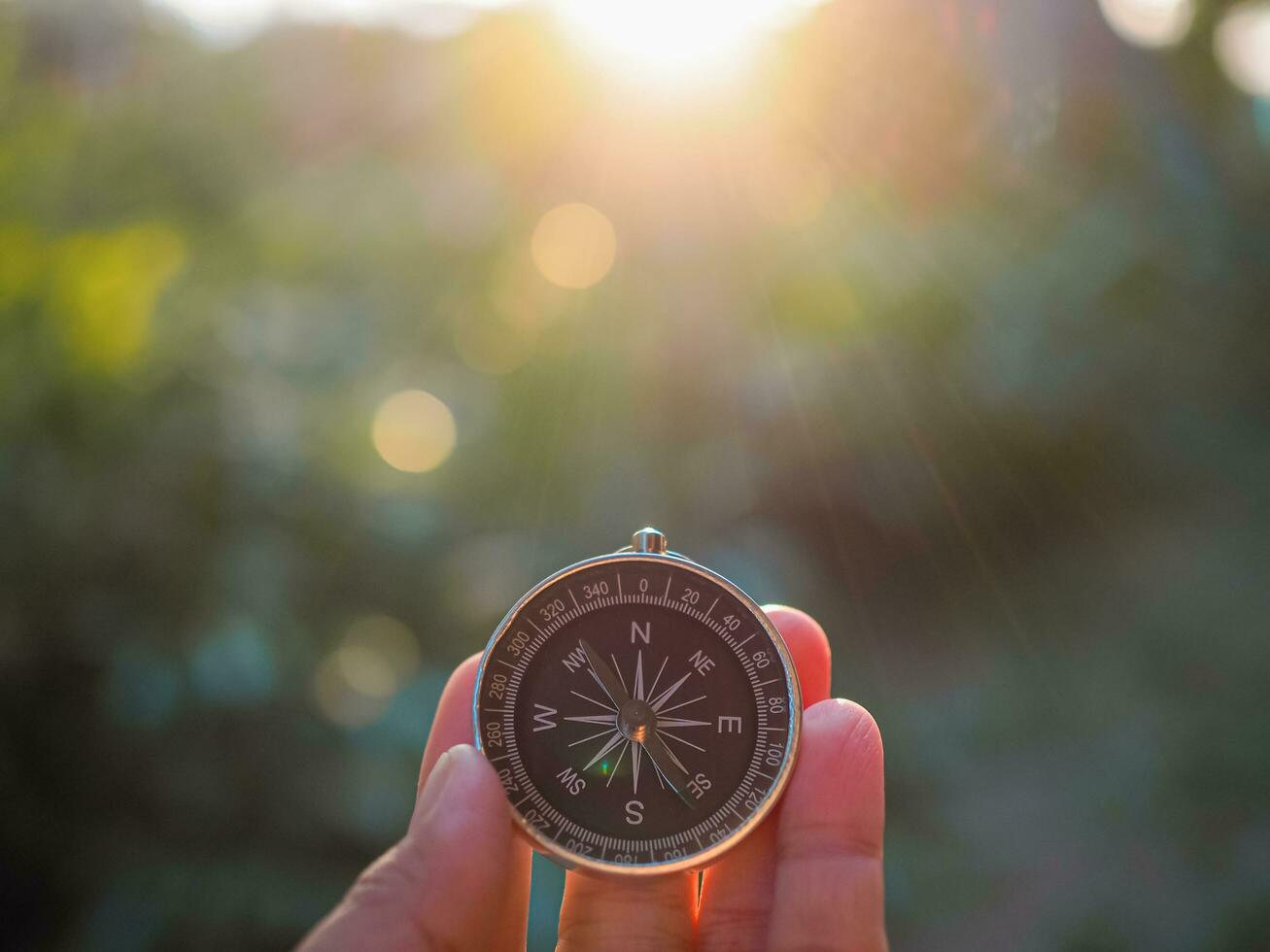 Hand holding compass with nature background. The concept of world tourism day, Searching the right directions and Travel photo