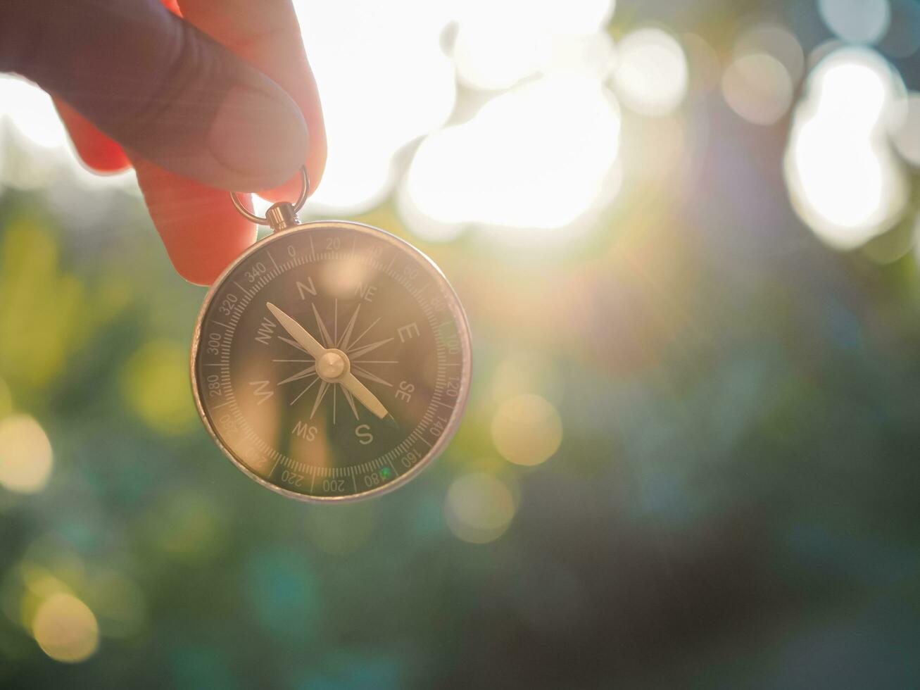 Hand holding compass with nature background. The concept of world tourism day, Searching the right directions and Travel photo