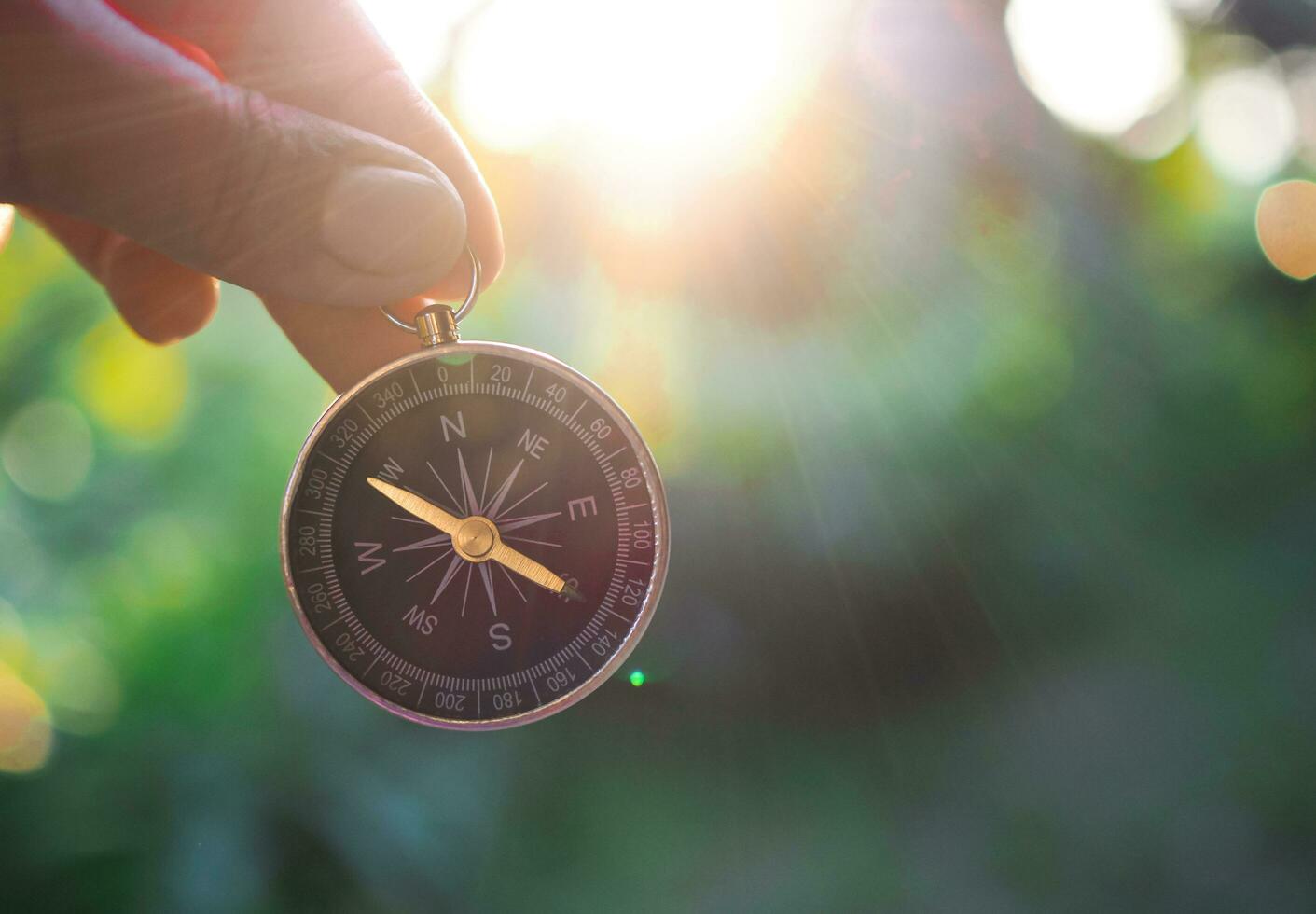 Hand holding compass with nature background. The concept of world tourism day, Searching the right directions and Travel photo