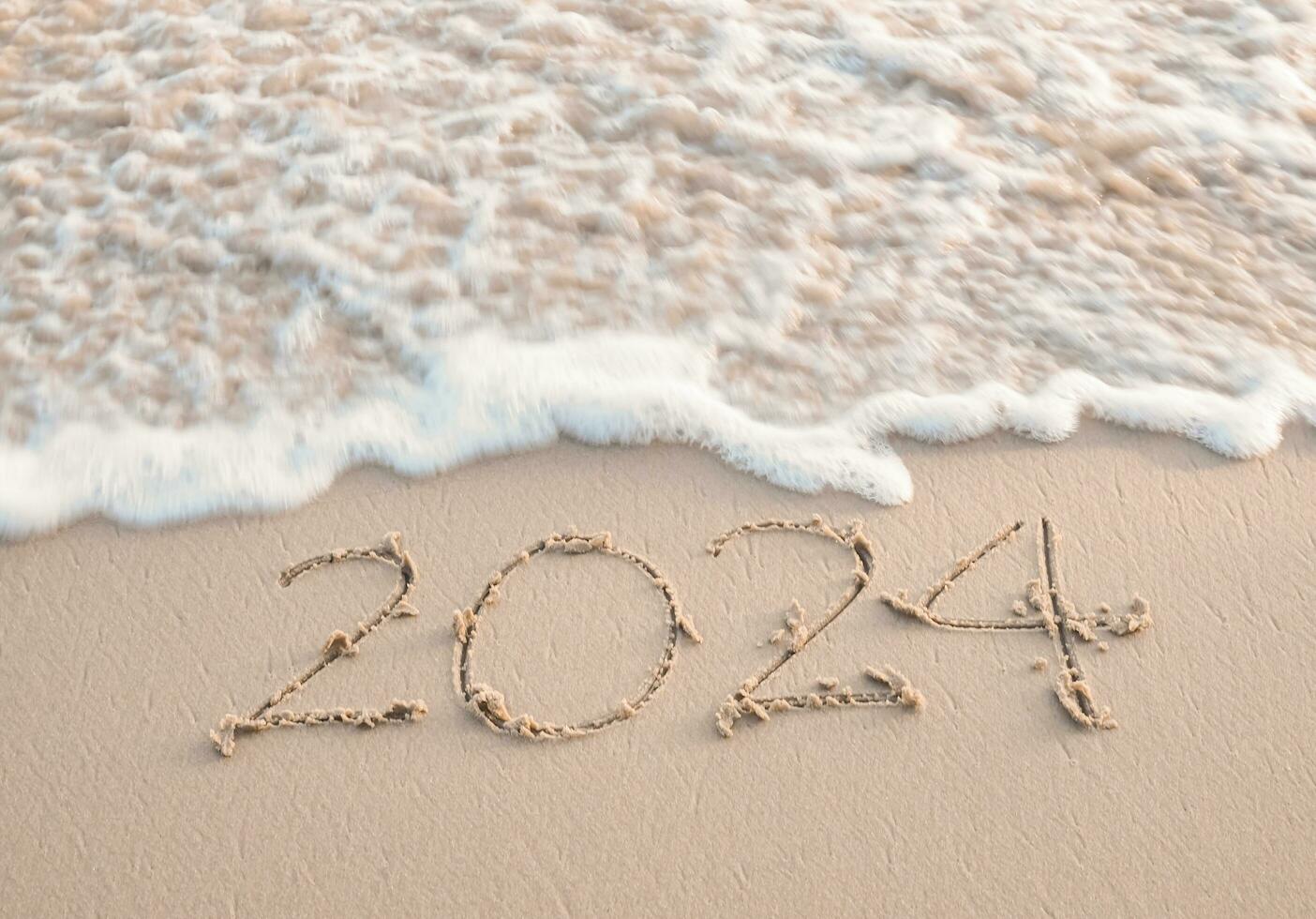 2024 año escrito en el playa en el puesta de sol tiempo. nuevo año 2024 concepto foto