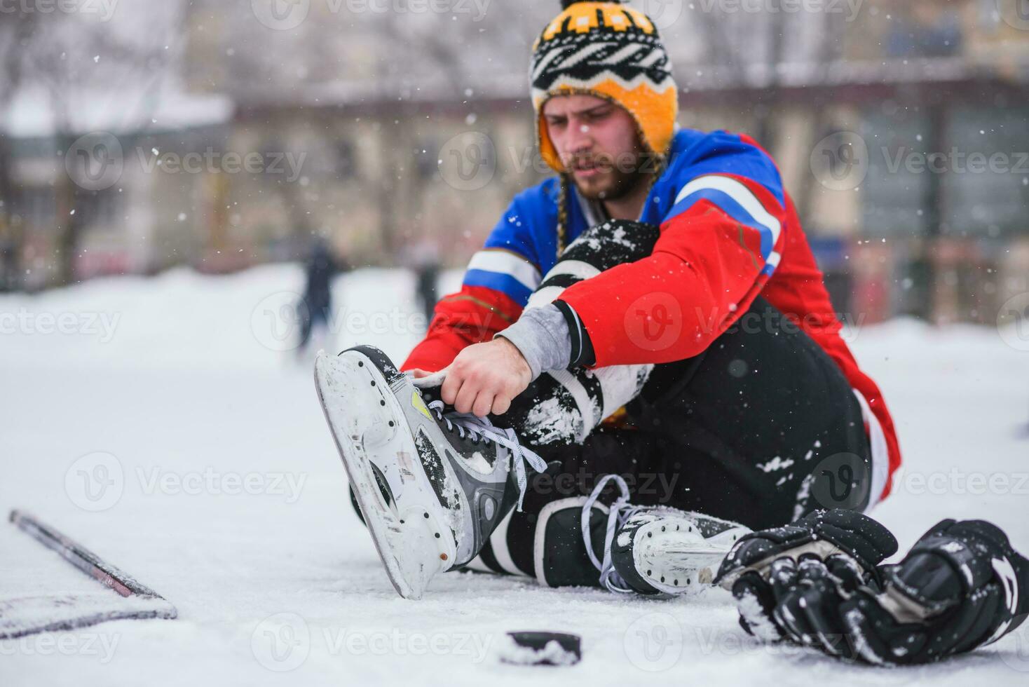 hockey player sitting on the ice to tie shoelaces photo