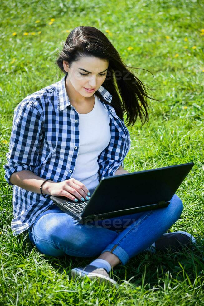 beautiful girl sitting in the park with a laptop photo