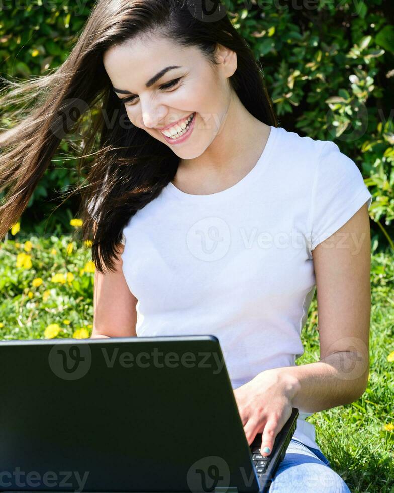 beautiful girl sitting in the park with a laptop photo