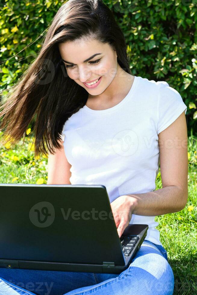 beautiful girl sitting in the park with a laptop photo