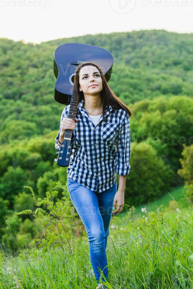 Girl goes through the hills with a guitar photo