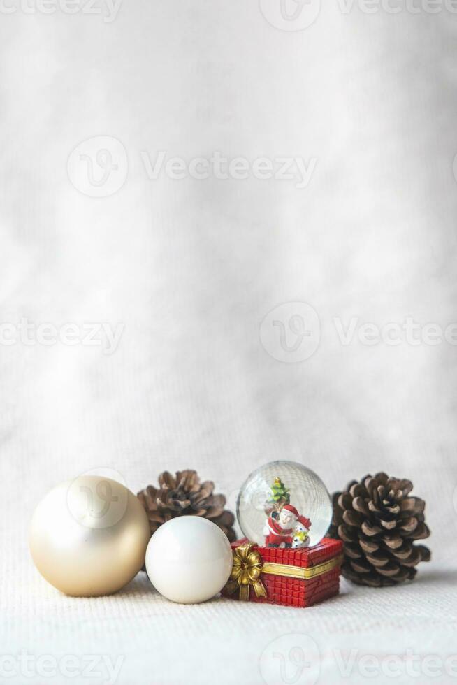 Navidad pelotas, Papa Noel claus en un nieve globo, y pino conos en un blanco paño, conjunto en contra un rojo antecedentes y Exquisito Bokeh. nuevo año celebracion atmósfera, acerca de de importante día. foto