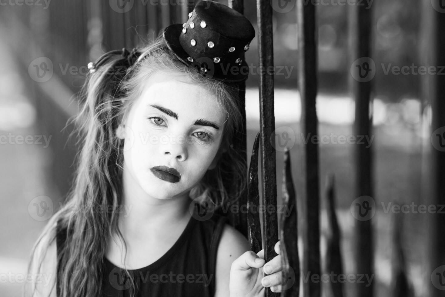 little girl mime is sad standing at the fence photo