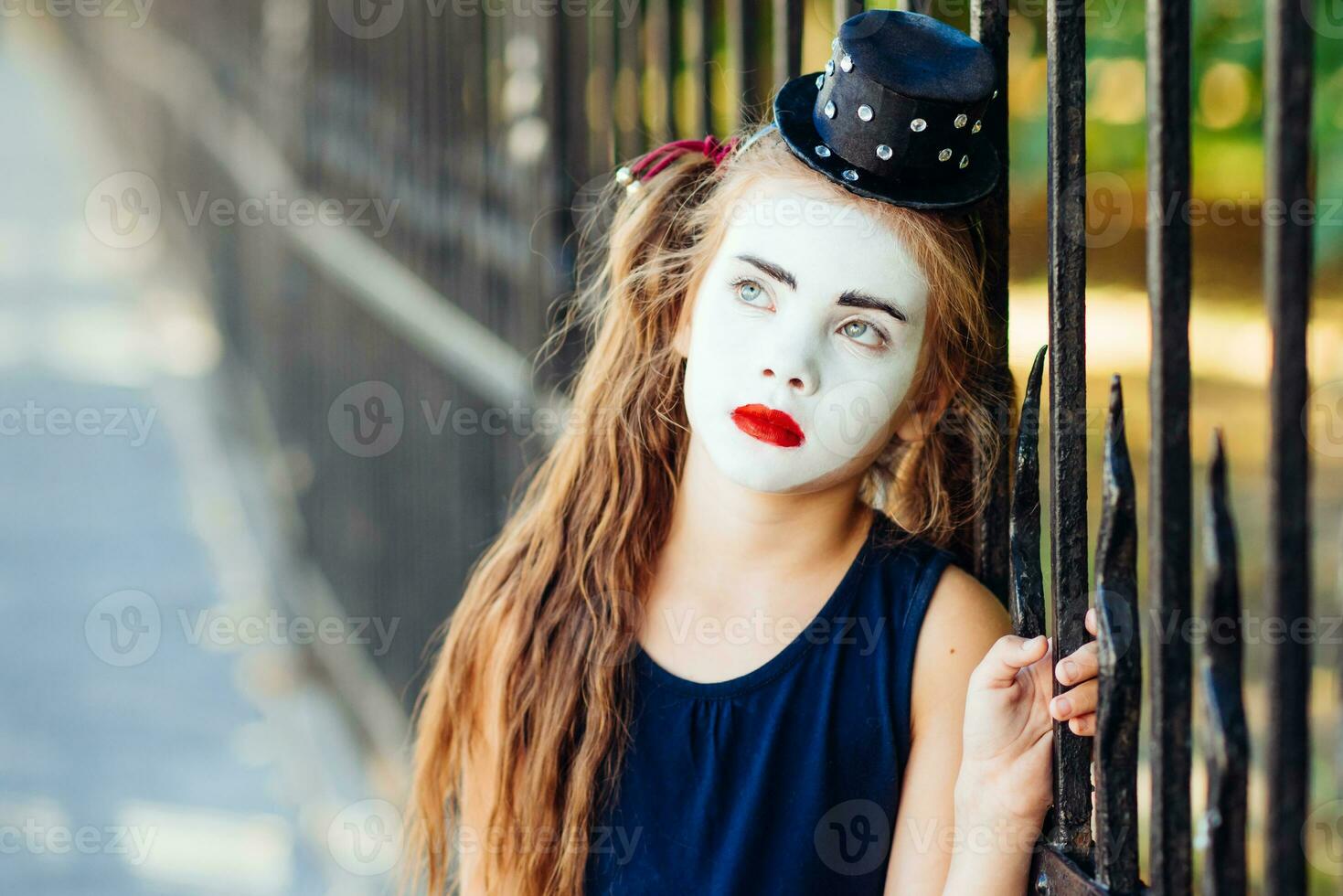 little girl mime is sad standing at the fence photo