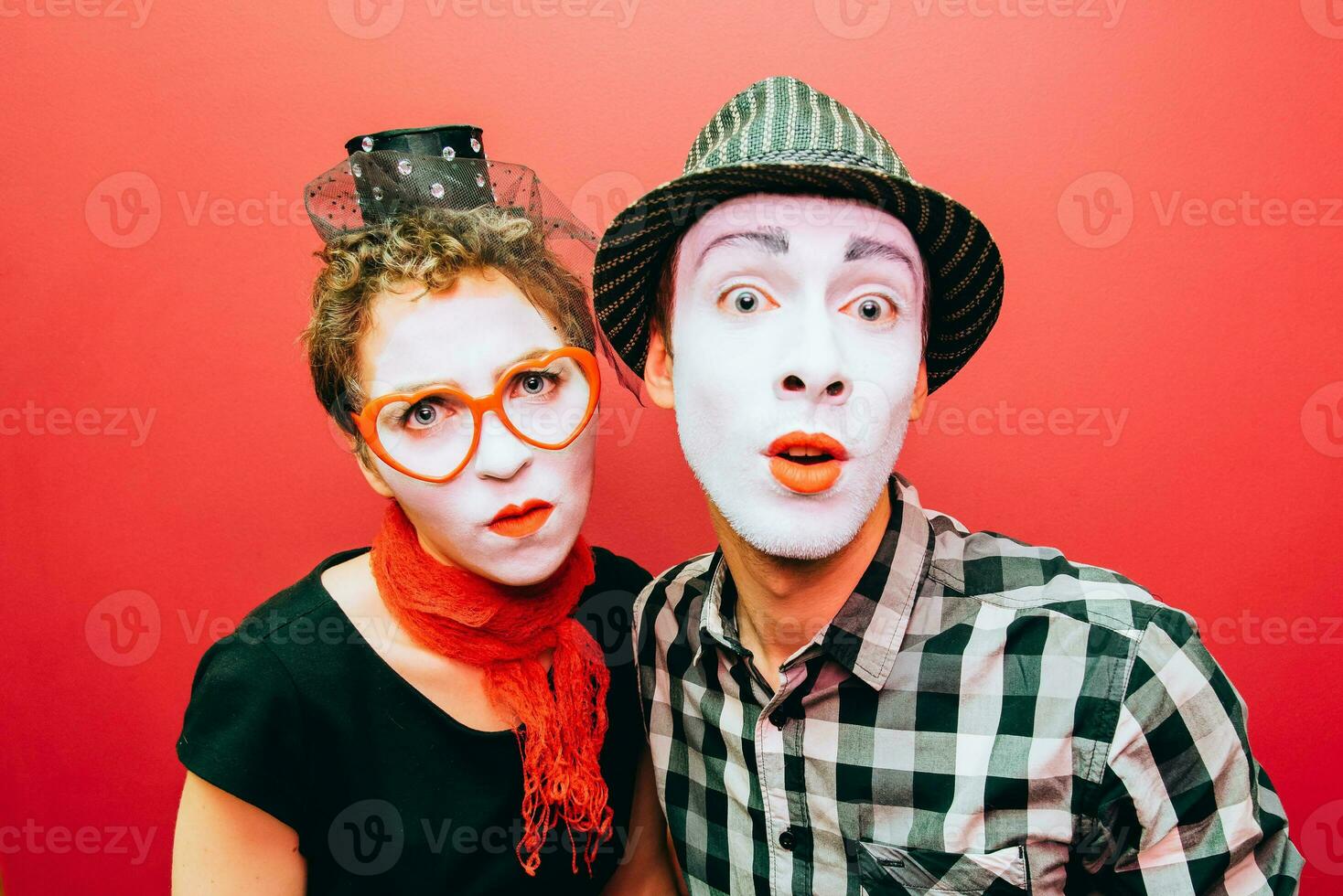 two mimes posing against a red wall background photo