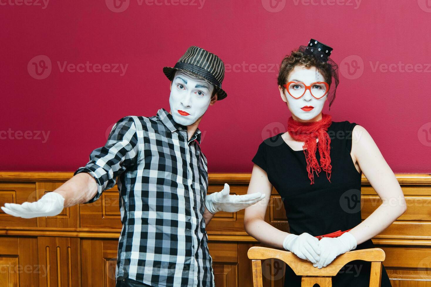 two mimes posing against a red wall background photo