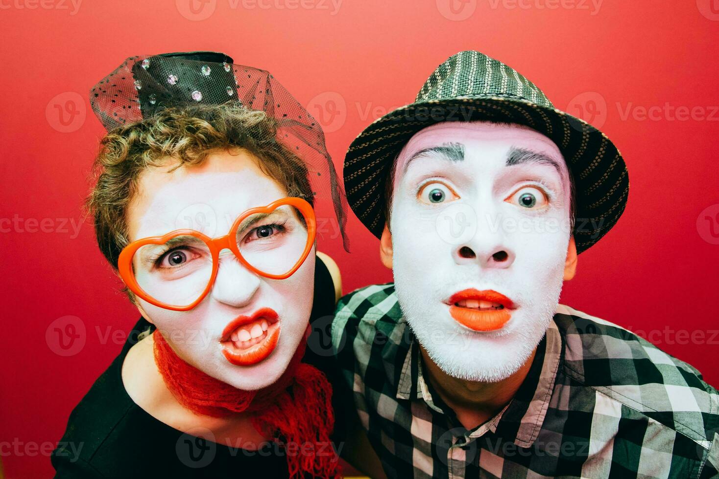 two mimes posing against a red wall background photo