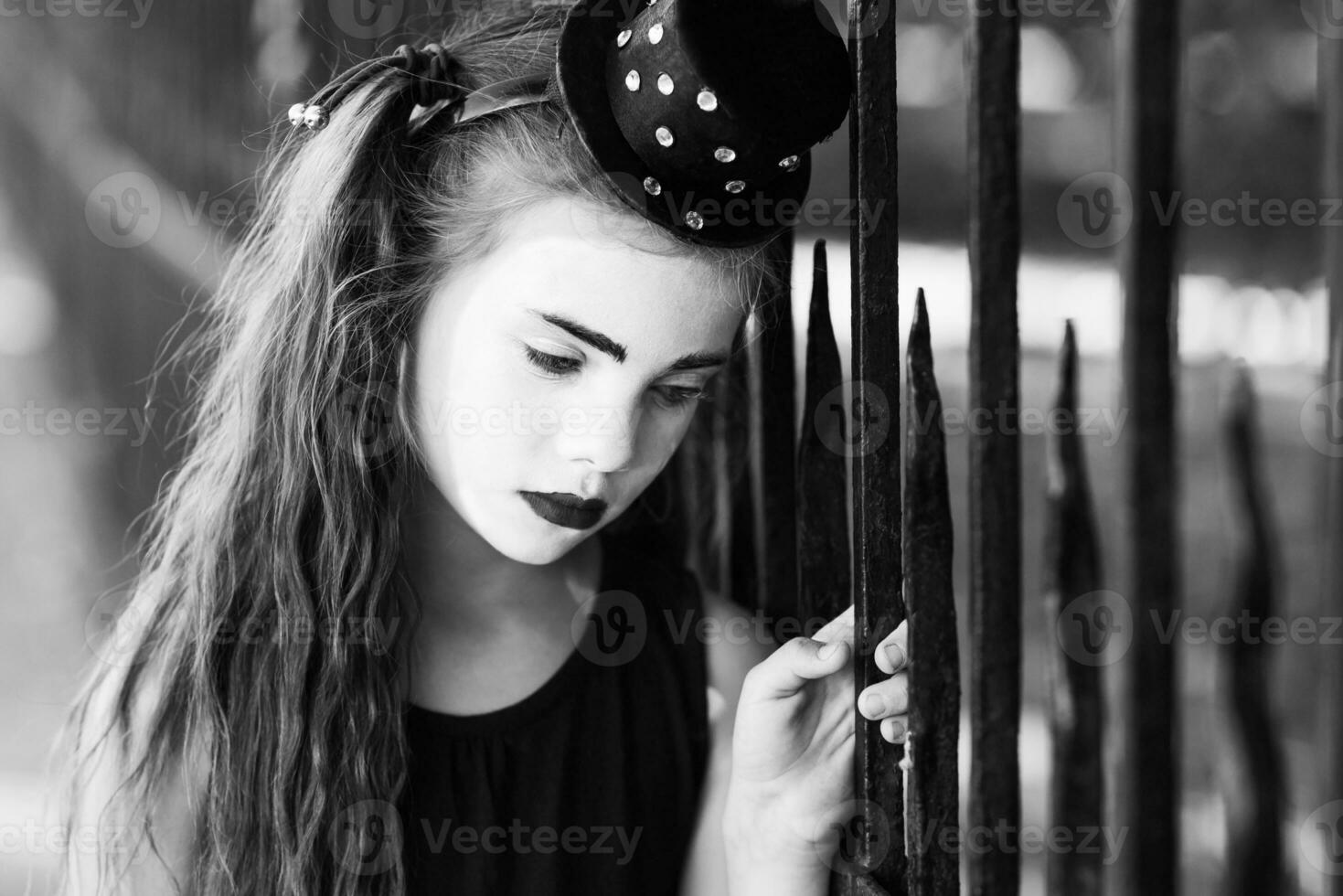 little girl mime is sad standing at the fence photo