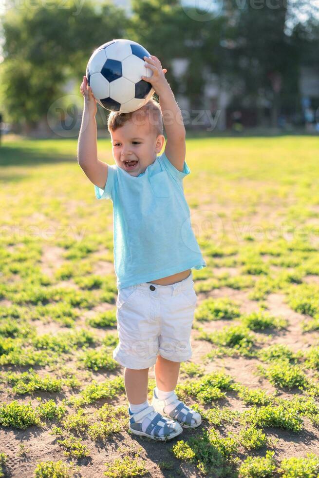 little boy playing with a soccer ball on the field in summer photo