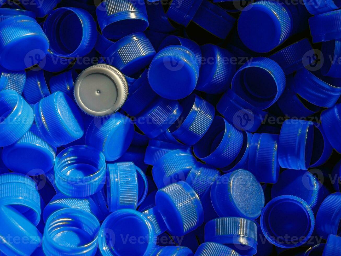 Grey plastic bottle caps on top to depict the concept of standing out from the crowd, dare to be different, odd man out, success or a leadership concept. photo