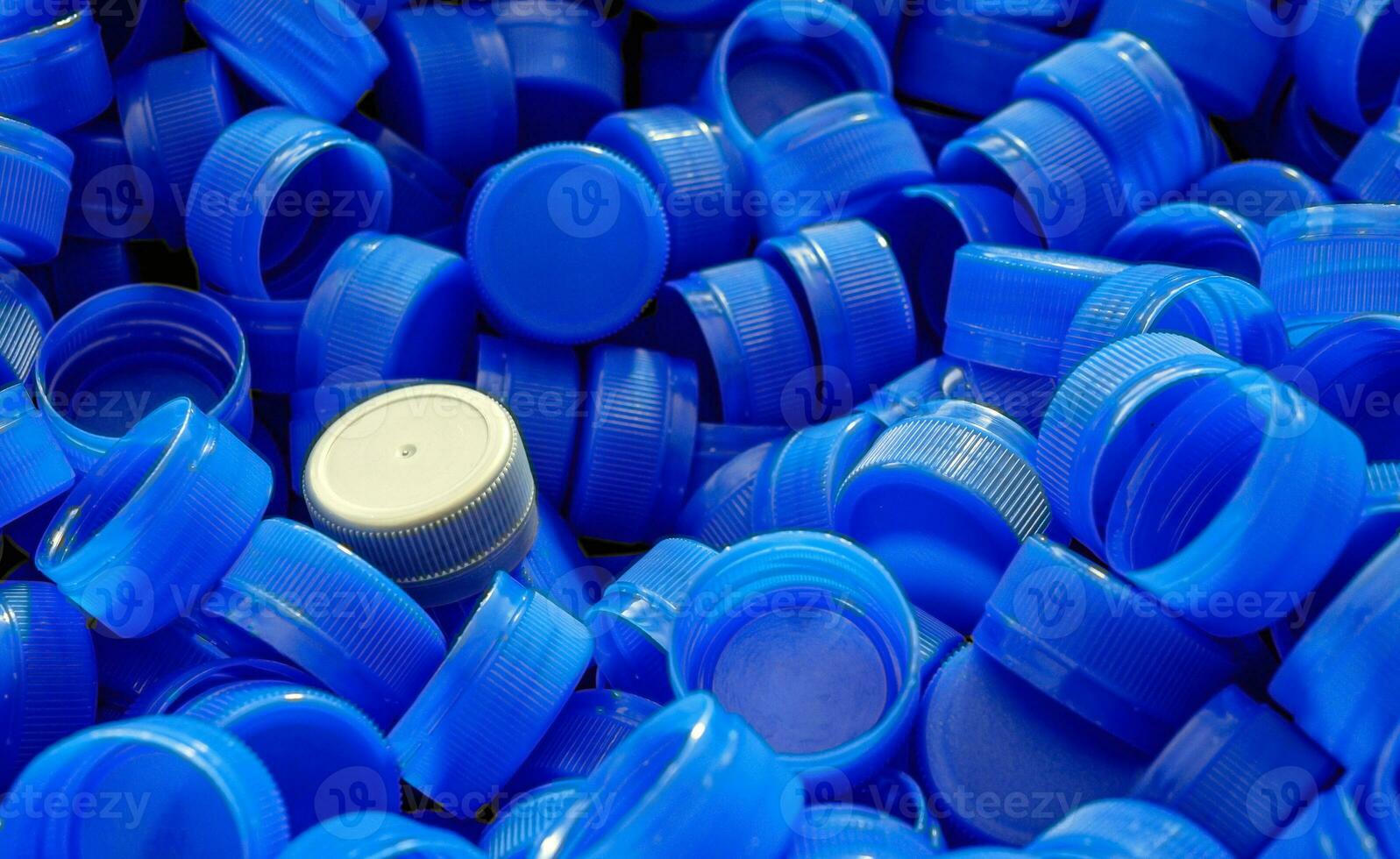 gris el plastico botella tapas en parte superior a representar el concepto de en pie fuera desde el multitud, atrevimiento a ser diferente, impar hombre afuera, éxito o un liderazgo concepto. foto