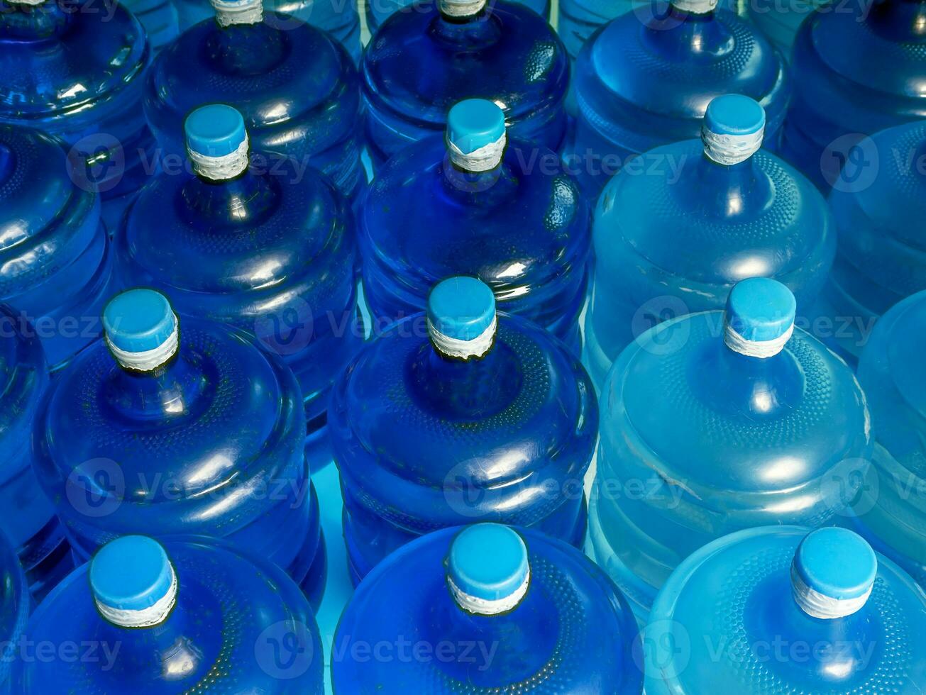 Top view of lined up plastic big bottles blue gallons of purified drinking water inside the production line. Water drink factory photo