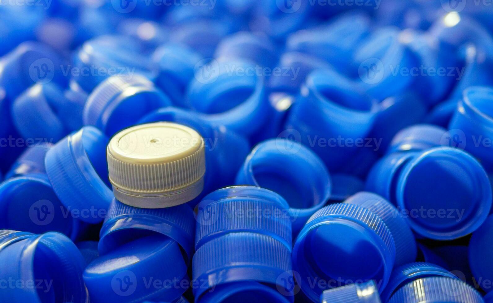 Grey plastic bottle caps on top to depict the concept of standing out from the crowd, dare to be different, odd man out, success or a leadership concept. photo
