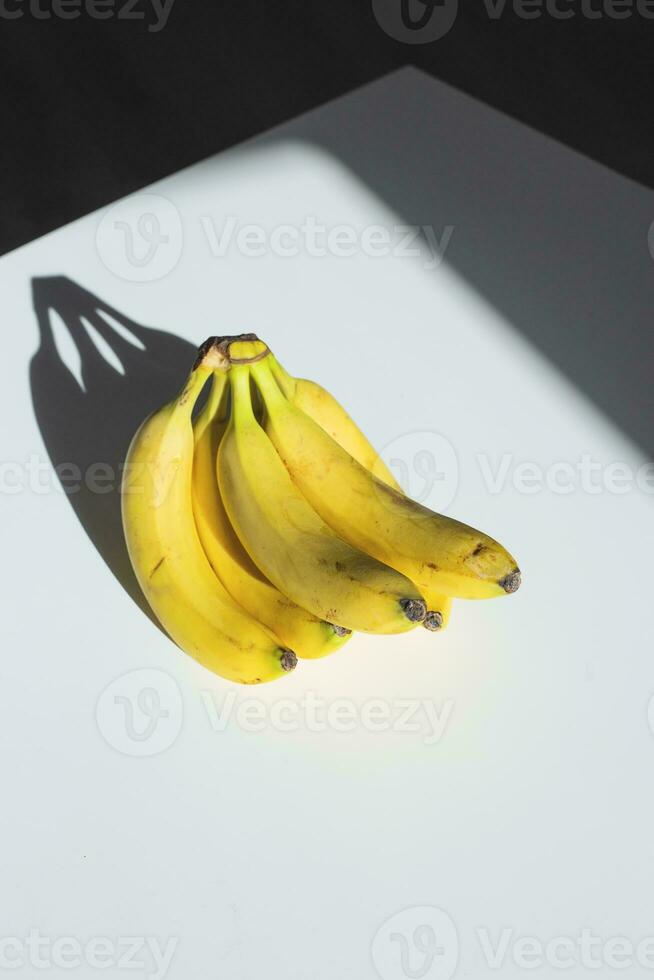 A bunch of bananas on a white table in sunlight. photo